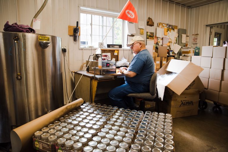A Gentle Breeze Honey employee bottles honey into jars.